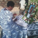 Prof Tibaijuka akisaini kitabu cha maombolezo katika msiba wa Ta Nshala